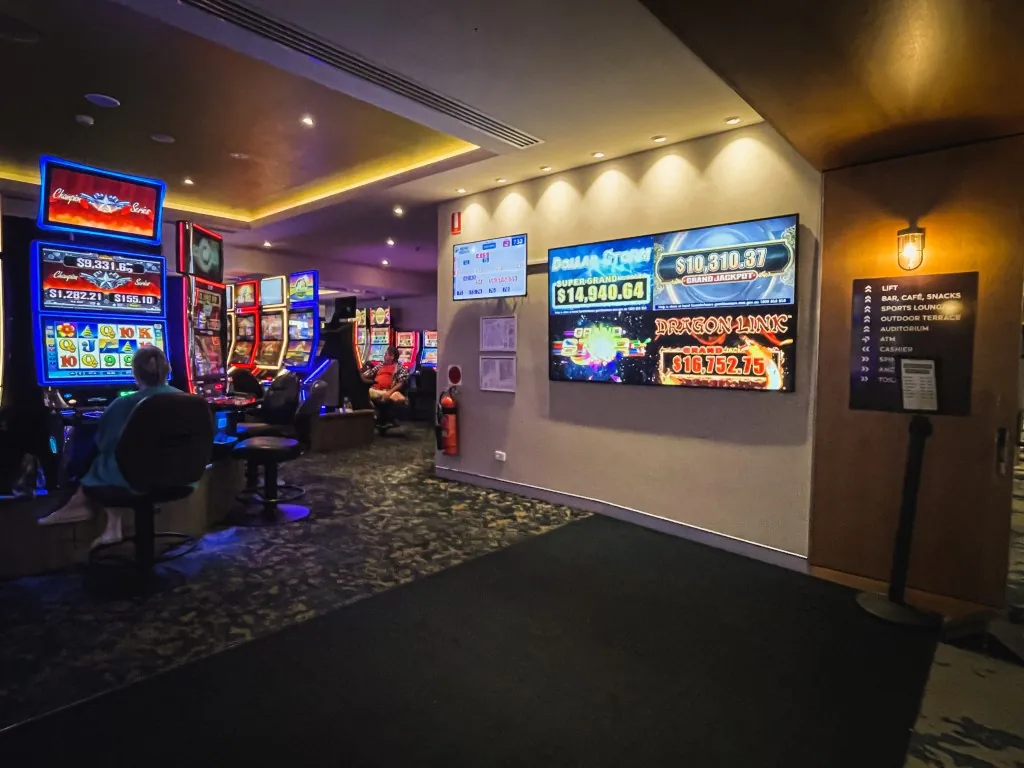 Jackpot and promo screens above a club gaming room