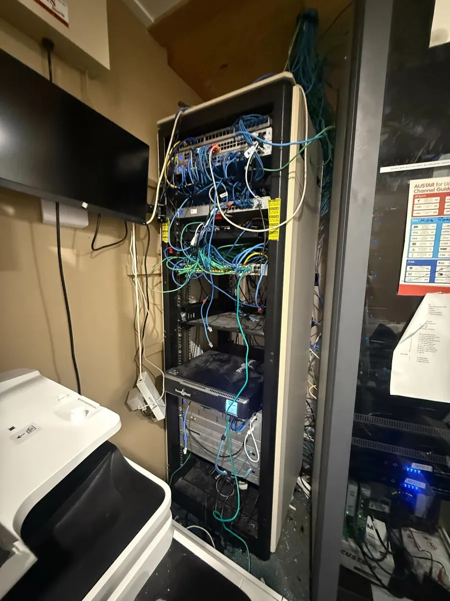 Comms rack before cleanup: tangled cables and unlabelled equipment