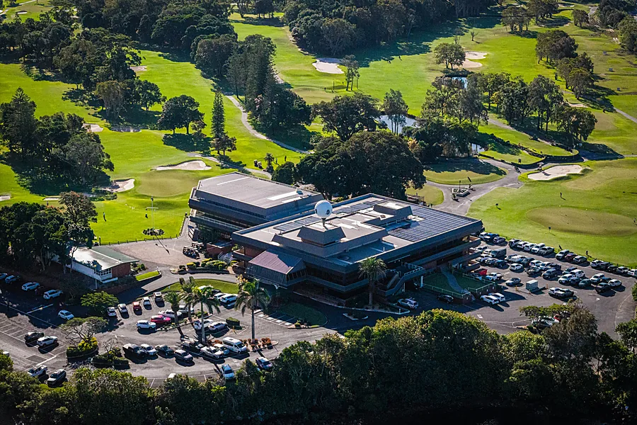 Close aerial over the Coolangatta & Tweed Heads clubhouse and its full car park, with greens and bunkers around it