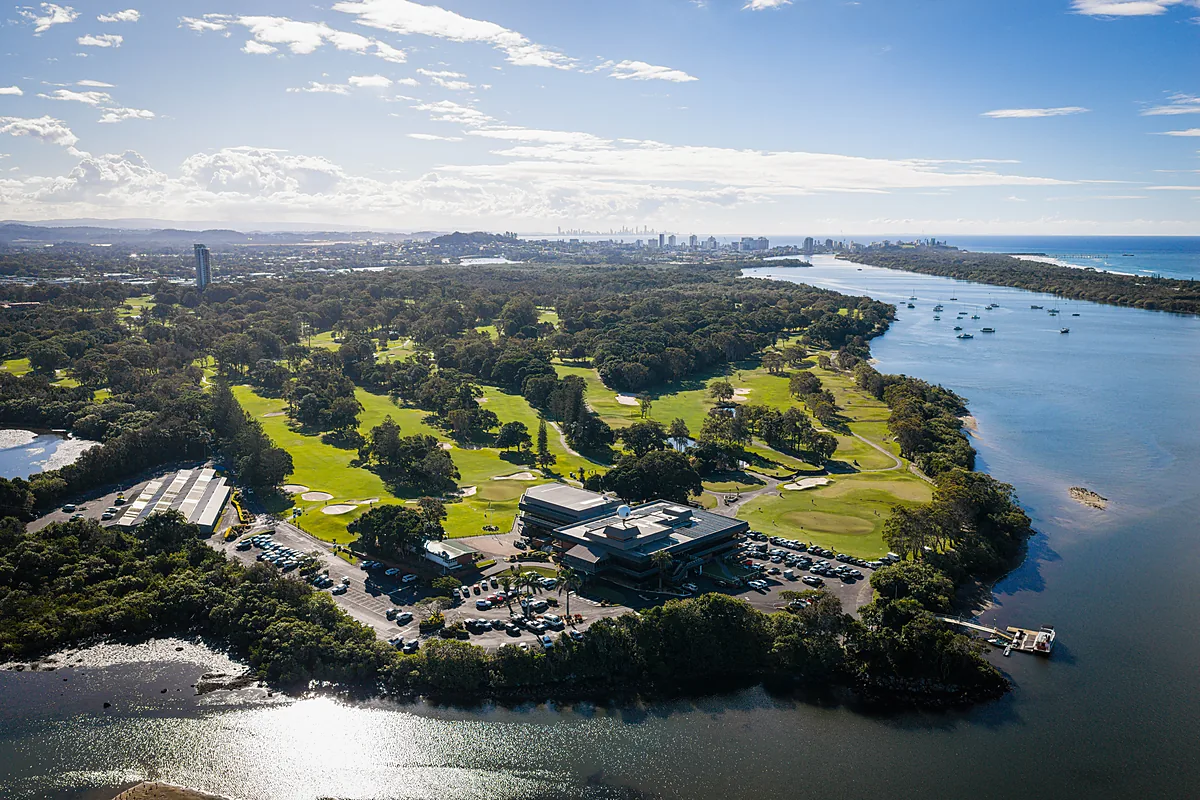 High aerial looking north over the Coolangatta & Tweed Heads golf course to the Tweed River mouth, moored boats and the Gold Coast skyline on the horizon