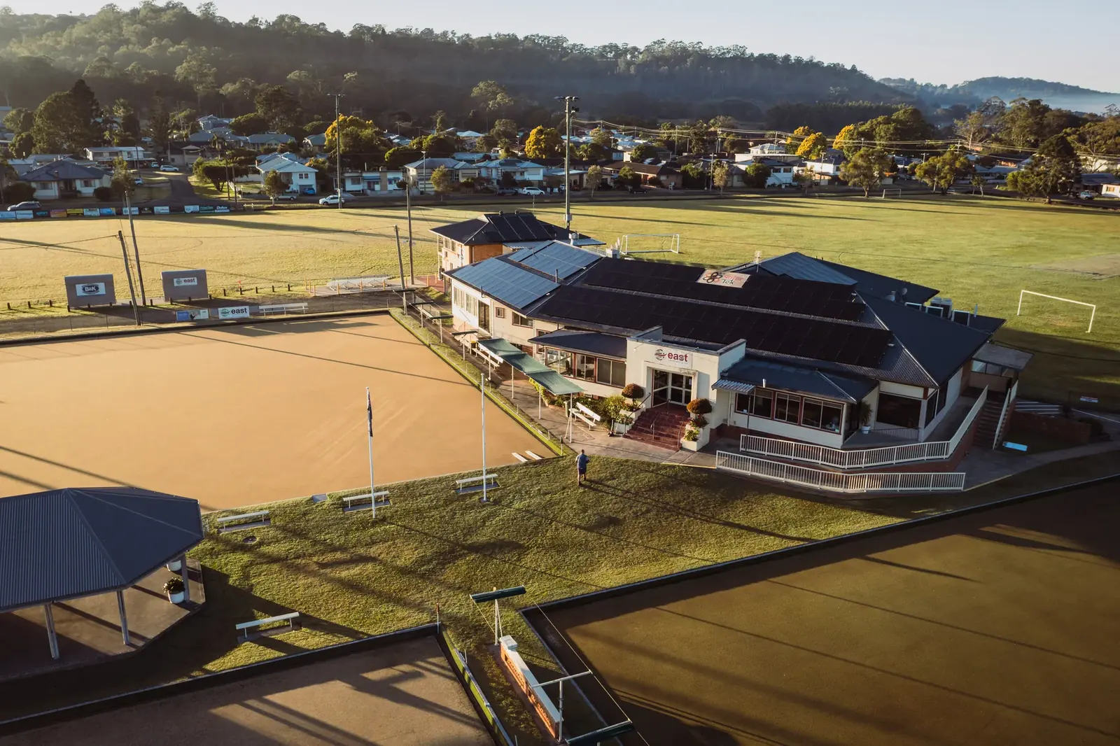 Dawn aerial of East Lismore Bowling Club — the clubhouse and greens with hills behind