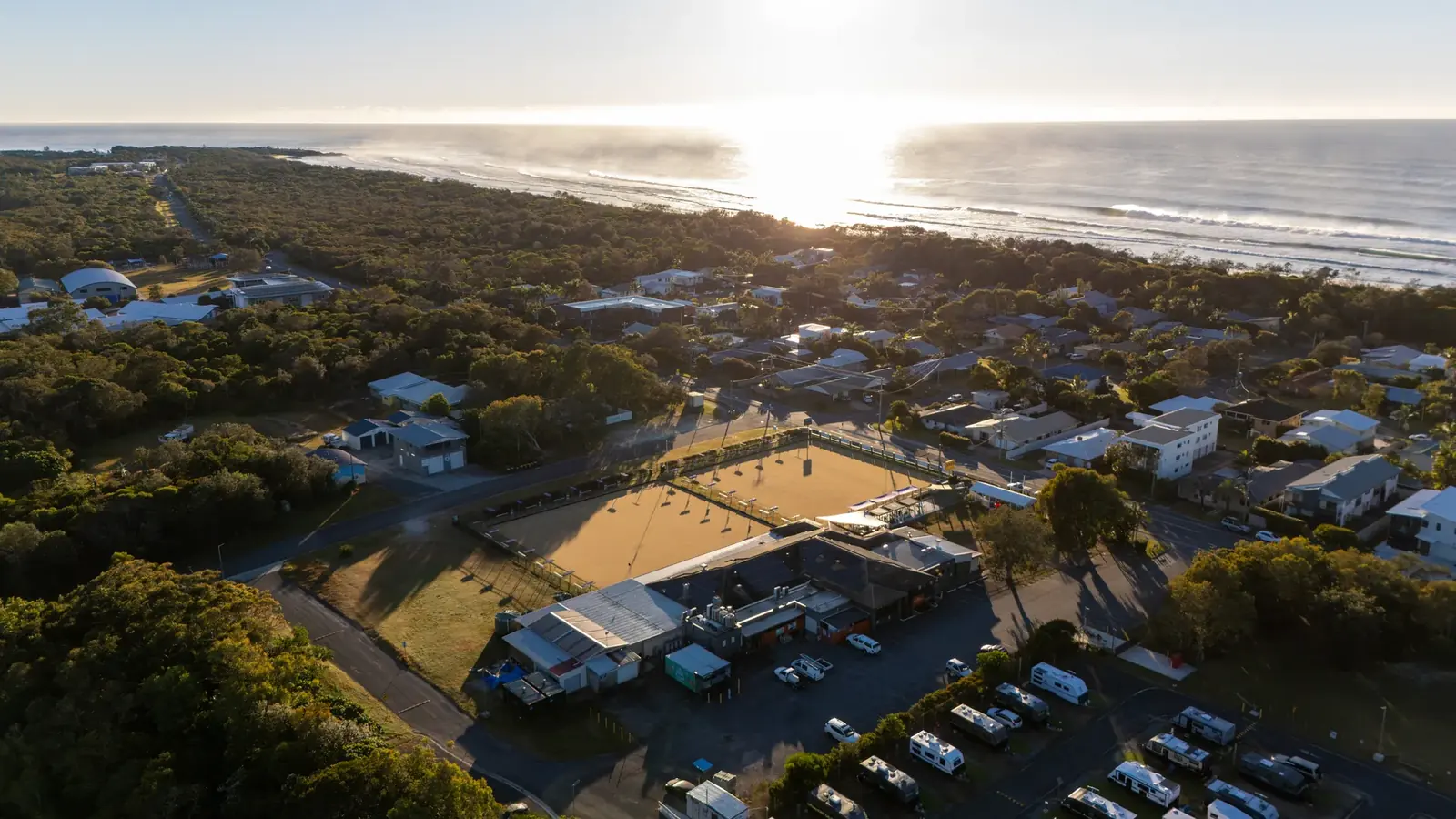 Golden-hour aerial of Pottsville Beach Sports Club with the ocean behind it