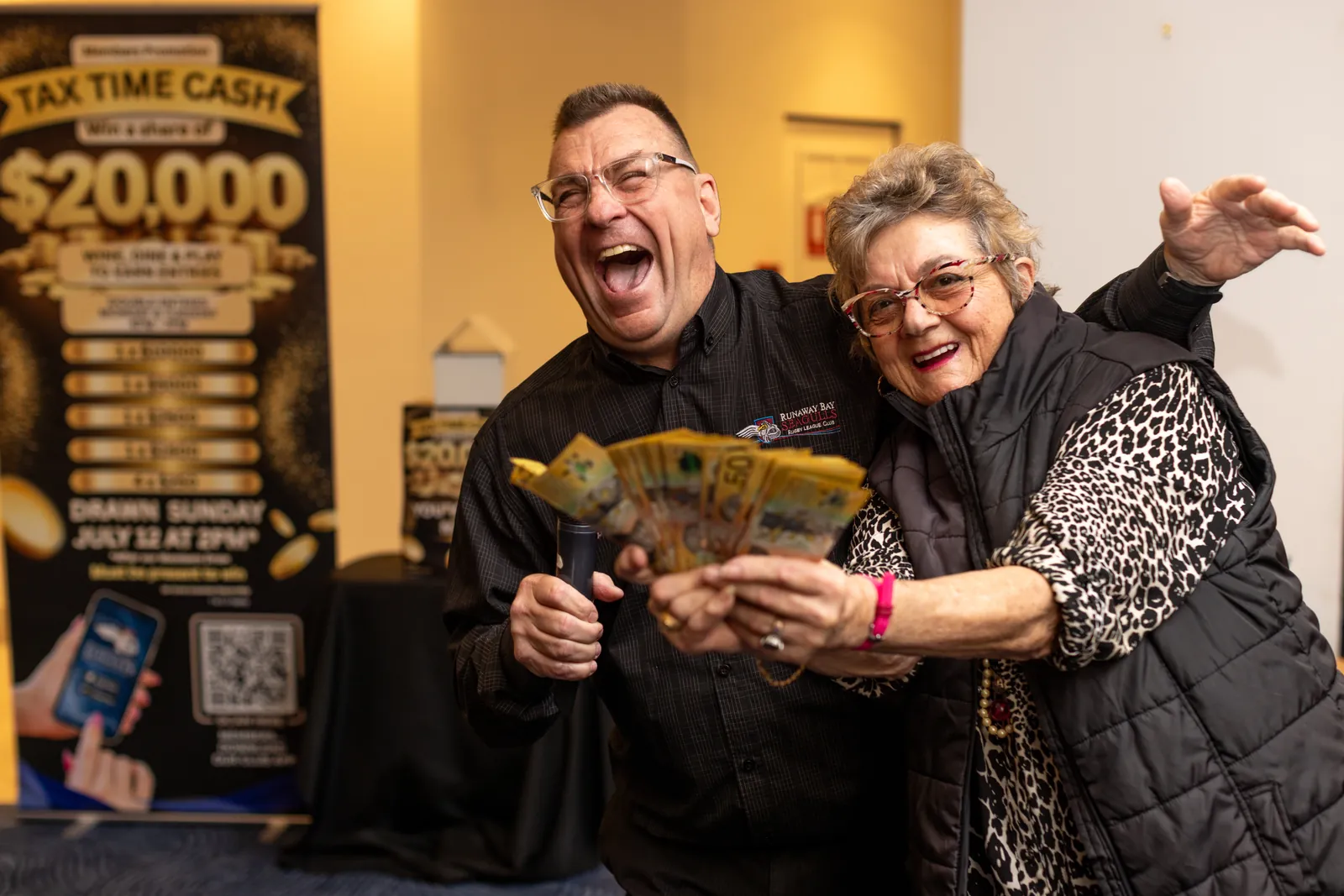 A delighted winner fans out fifty-dollar notes at the twenty-thousand-dollar Tax Time Cash draw