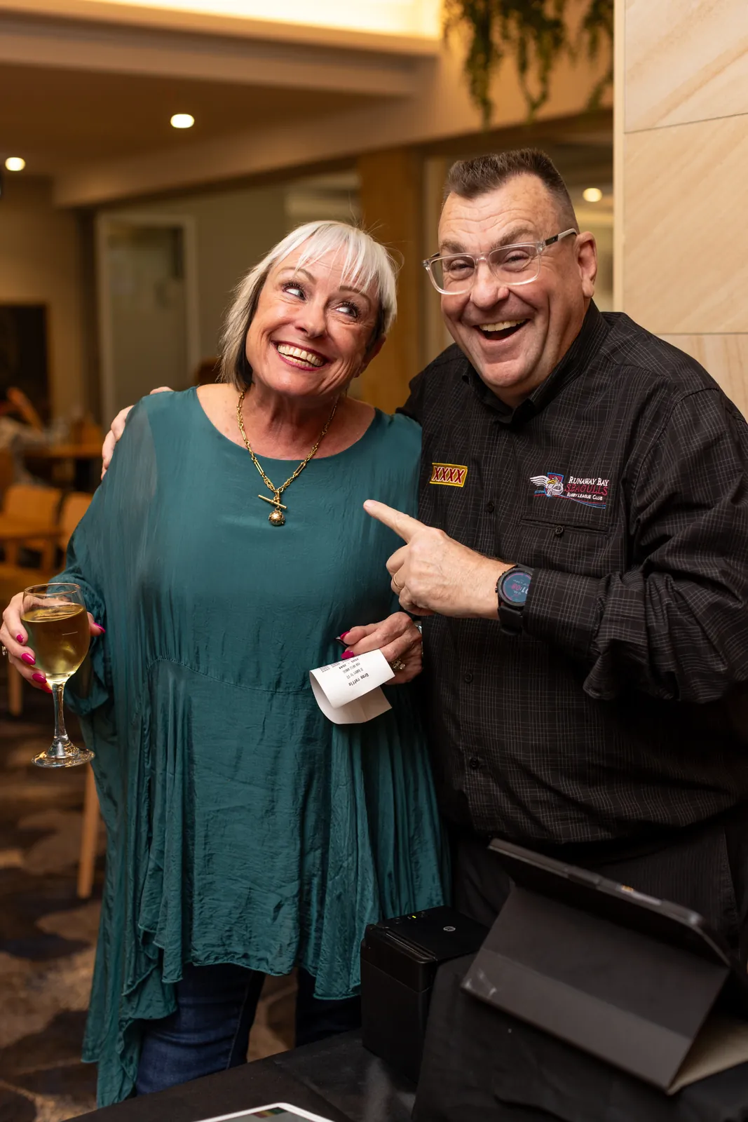 A staff member sharing a laugh with a raffle-winning patron at Runaway Bay Juniors